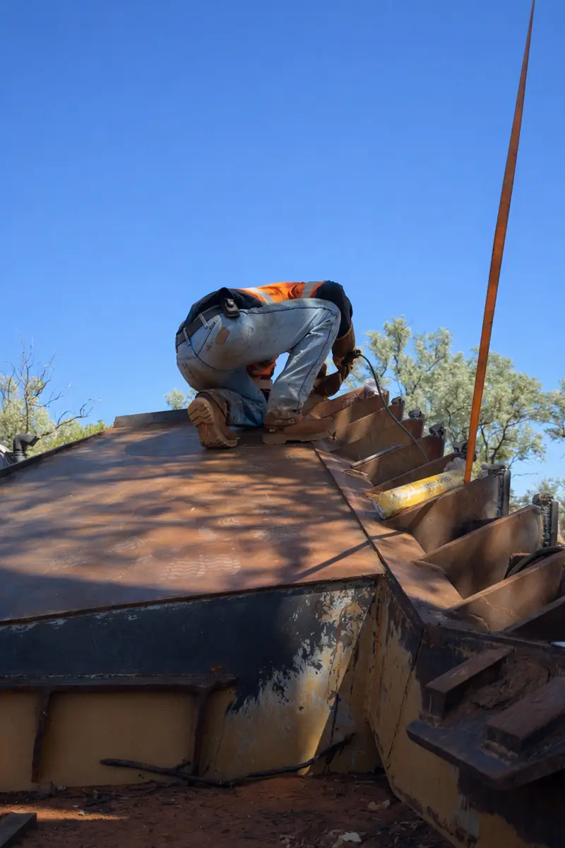 Welding a stick rake for a D8 dozer out on red dirt