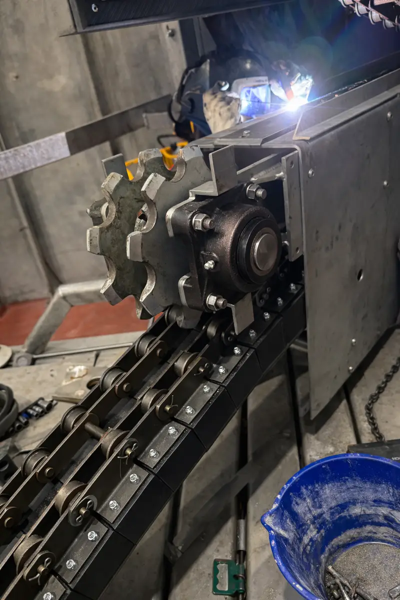 Welding a sprocket drive on a chain conveyor inside a plant