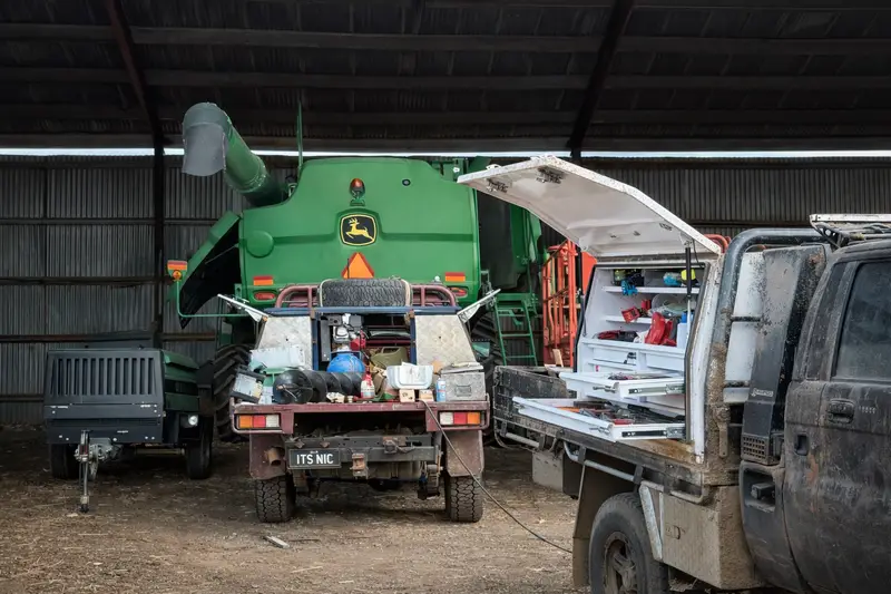 Agrimec service ute beside a John Deere header in the machinery shed